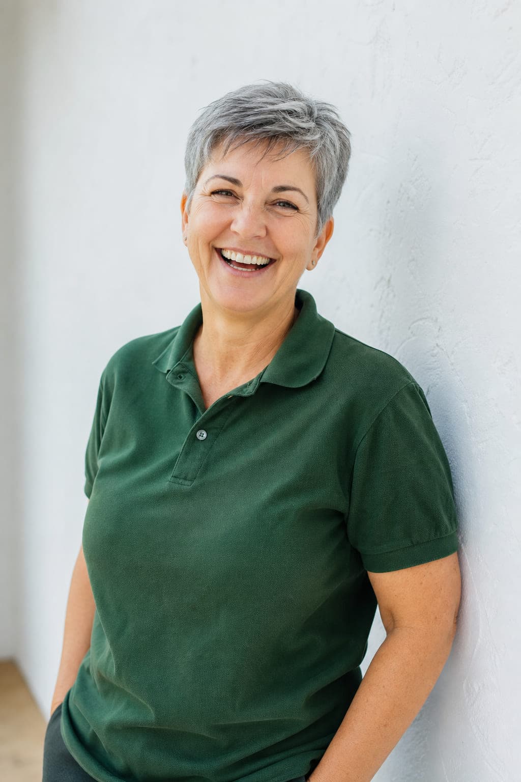 Portraet von Carola Rennwald, laechelnd vor einer hellen Wand.